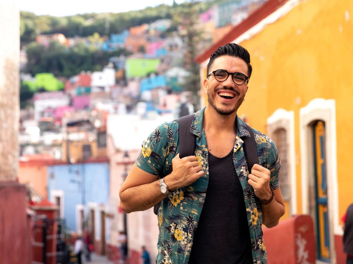 Viajero sonriendo con su mochila en una calle colorida