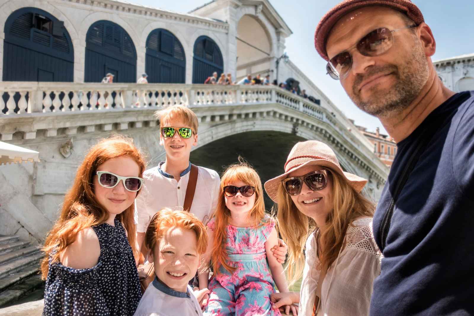 Familia con dos adultos y dos niños de espaldas caminando por una plaza mientras miran un mapa