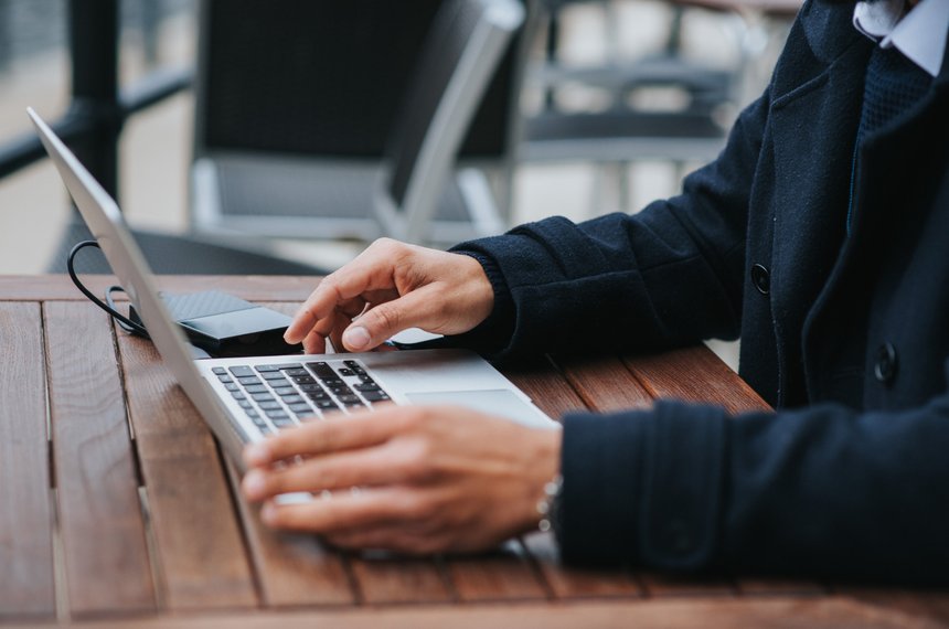 Laptop y teléfono sobre una mesa de cafetería, conectados a internet mediante un punto de acceso