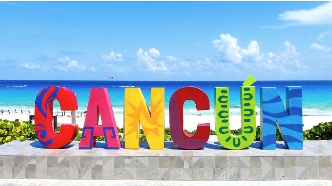 Letrero colorido de Cancún frente a una playa de mar turquesa